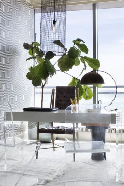 a fancy home office with a concrete and acryl desk, acrylic chairs and a leather one, a bold potted plant and a unique light