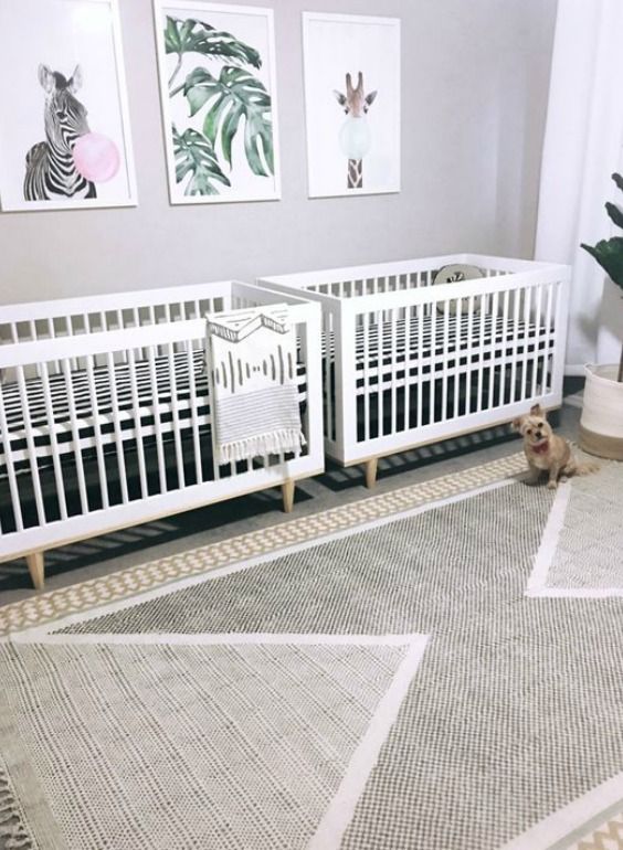 a fun contemporary twin nursery with two white cribs, a gallery wall, printed textiles and a potted plant is cool