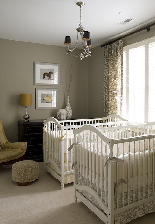 A grey and yellow mid century modern nursery with white cribs, a black dresser, a chic chandelier and a yellow chair