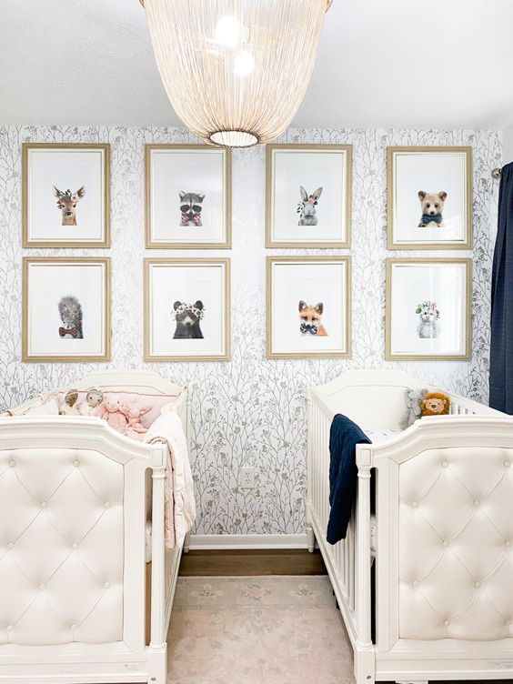 A lovely nursery with ana ccent wall, white tufted cribs, a gallery wlal with animal and navy black out curtains