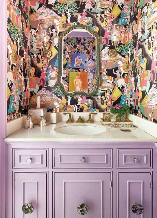 a maximalist bathroom with crazily printed wallpaper, a lilac built-in vanity and a mirror in a vintage frame is chic