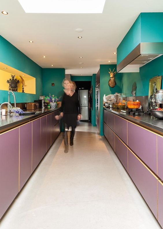 a maximalist kitchen with green walls and a hood and purple lower cabinets, a yellow niche and taxidermy