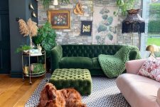 a maximalist living room with a faux stone wall, a green and a pink sofa, a green ottoman, a printed rug and potted plants is chic