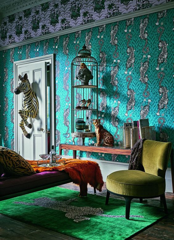 a maximalist living room with catchy green wallpaper, a cage with art and shoes, a leopard figurine and a zebra coming through the door, jewel tone furniture