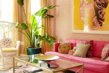 a maximalist living room with pink wallpaper walls, a hot pink sofa, a peacock chair, a glass coffee table, a colorful floral rug and yellow curtains