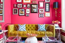 a maximalist living room with pink walls, a super bold rug, a mustard sofa, a bold gallery wall and ghost chairs