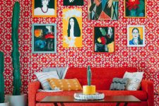 a maximalist living room with red printed wallpaper, a red sofa, potted cacti, a colorful gallery wall and a coffee table