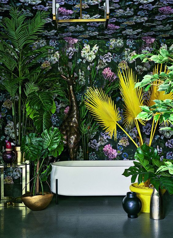 a maximalist space with dark floral wallpaper, bold statement plants in green and yellow, brass touches and vases