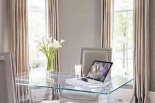 a refined and sleek home office with neutral walls and matching curtains, a sheer desk and refined upholstered chairs