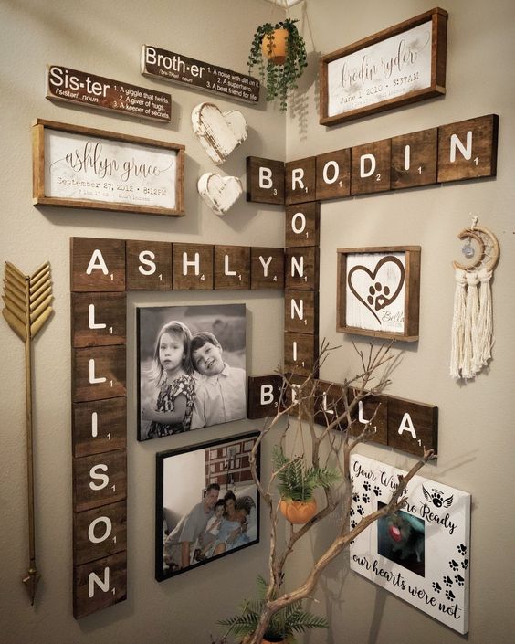 a rustic and boho gallery wall with wooden letters, signs in frames, some branches, arrows, tassels and potted greenery
