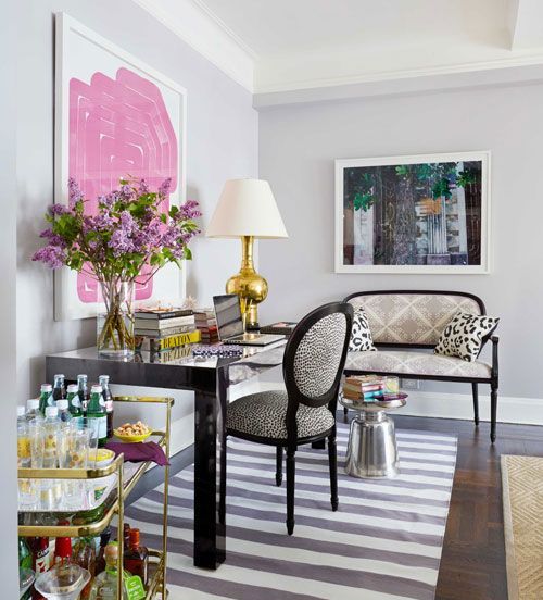 a sophisticated home office with a black desk and animal printed textiles, a striped rug, bold artworks and a gold bar cart is chic