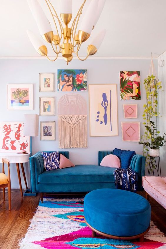 a super colorful maximalist living room with a blue accent wall, a bold blue sofa and ottoman, a colorful gallery wall and potted plants