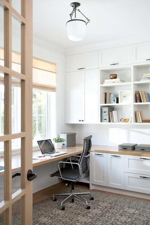 a modern farmhouse home office with white shaker kitchen cabinets, a floating desk and shades plus a printed rug