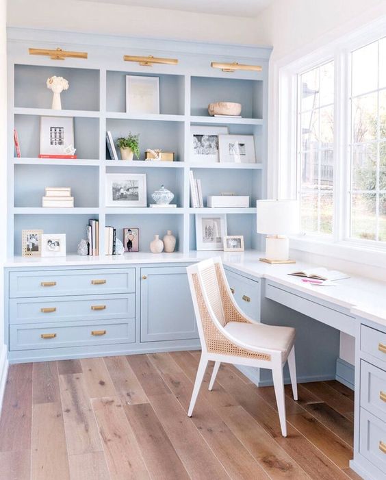 a beautiful coastal home office done in light blue, done with kitchen cabinets and a matching desk and gold touches
