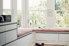 07 a chic space with corner windows, a large double daybed with storage drawers and more storage around, a boho rug and a wooden bead chandelier