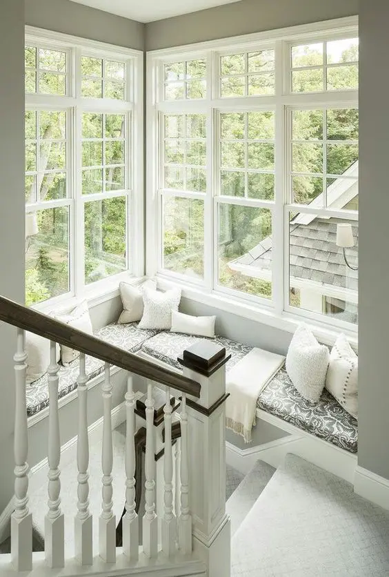 a corner window at the staircase with a large daybed with pillows and a blanket to enjoy a book and a cup of tea with a view