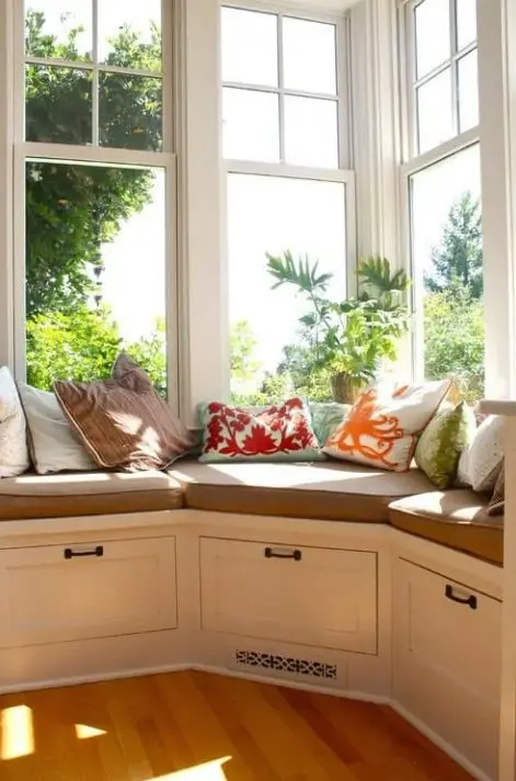 a corner window with a windowsill daybed, with drawers for storage and colorful pillows is a lovely space to spend your time here