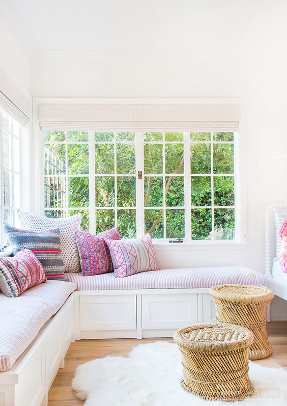 a cozy and inviting nook with a corner window, a corner daybed with colorful pillows and rattan stools is very chic and lovely