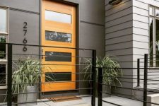 15 a stylish modern entrance with grey walls, a glass insert stained door, grey planters with greenery that features a lot of texture