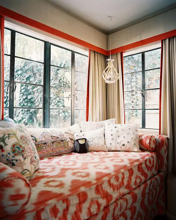a gorgeous and bright corner space with a corner window, a colorful sofa with lots of pillows just welcomes to stay here