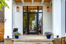 17 a modern and fresh porch with a glass door, bold blue planters with lilac blooms and a hanging chair plus lanterns on the walls