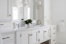 19 a gorgeous master bathroom with creamy shaker style cabinets from the kitchen, a double mirror and sink, sconces and a chic floor