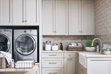 23 a gorgeous dove grey laundry room done with shaker style kitchen cabinets, a brick wall, potted plants and a cool tile floor