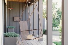 25 a modern porch with pillars, a planked wooden floor, a hanging metal chair, metal planters with greenery looks ultimate chic