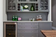 31 a chic grey home bar with kitchen cabinets – glass and usual ones, a beadboard backsplash and a wine cooler