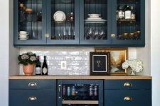 33 an elegant home bar done with navy kitchen cabinets, glass and usual ones, with a wine cooler and a subway tile backsplash plus a butcherblock countertop