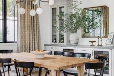 35 a stylish dining room with lower kitchen cabinets with glass doors, a wooden dining table and black chairs