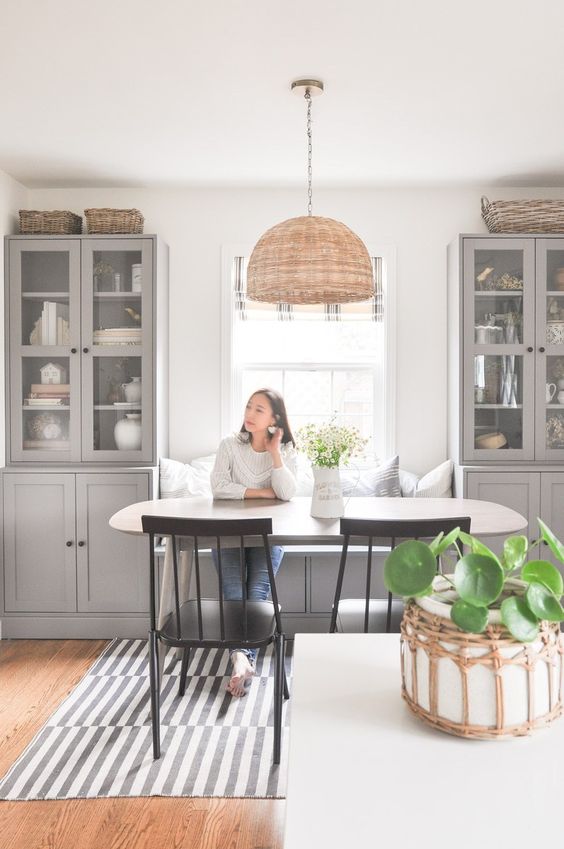 a cozy and welcoming dining room with grey shaker kitchen cabinets, an oval table and black chairs, a pendant lamp