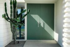 a beautiful modern entrance with green fluted doors and a cactus planted by the window is a cool and laconic space