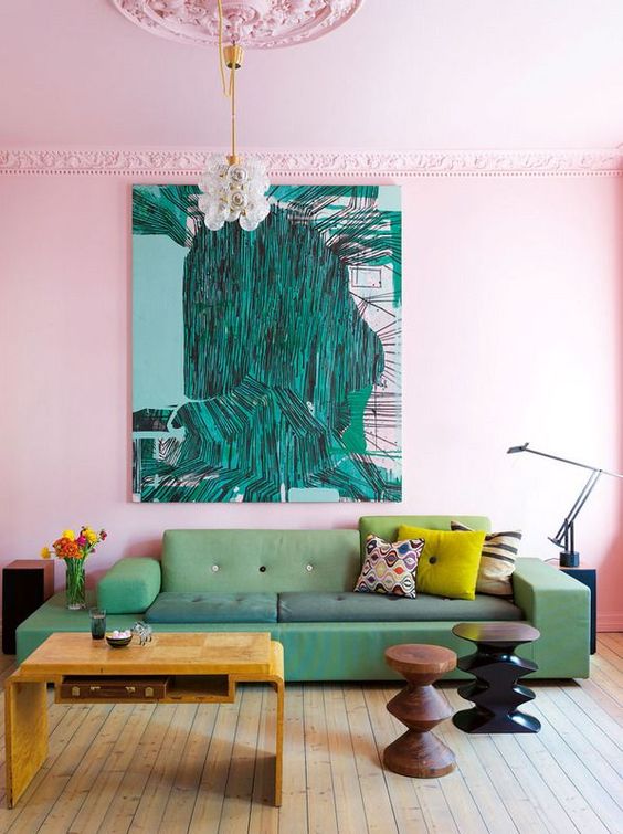 a bright living room designed with a pink accent wall and a ceiling, a catchy green sofa, carved side tables and a gorgeous statement artwork