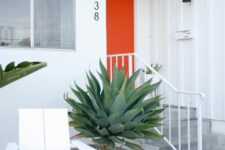 a catchy modern entrance with an orange door, a black spotlight, a white lounger and a couple of large agaves