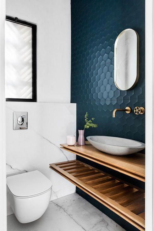 a chic modern restroom with a navy hexagon accent wall, floating shelves, a bowl sink and marble tiles cladding the wall and the floor