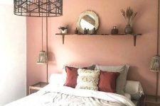 a cool boho bedroom with a pink accent wall, a comfy bed with pretty bedding, a little shelf with some decor and woven pendant lamps