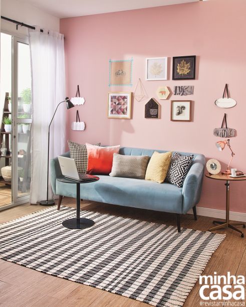 a cute modern living room with a pink accent wall and a gallery wall on it, a blue sofa, some coffee tables, printed textiles is sweet