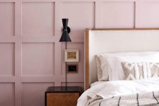 a dreamy bedroom with a pink panel accent wall, a bed with an accent headboard, a catchy nightstand and a chic black sconce plus a pink rug