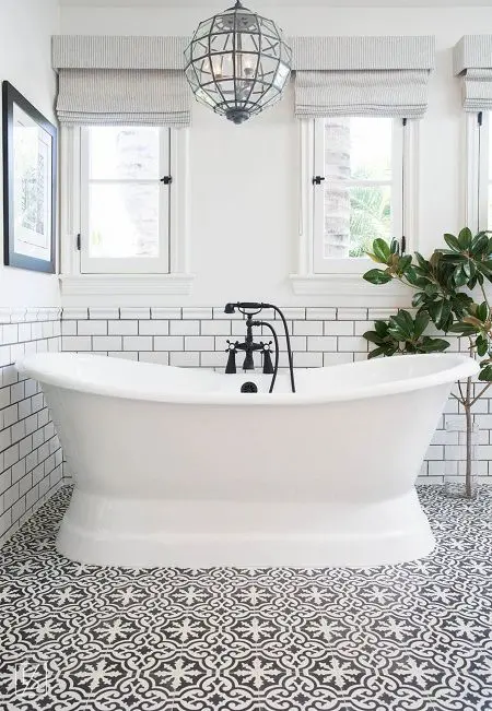 a fancy bathroom with a beautiful mosaic tile floor, a lovely tub and a chic faceted pendant lamp plus a statement plant