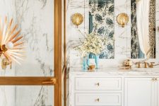 a fancy bathroom with white marble, a teal ceiling, white cabinets, gold touches and quirky lamps is a chic and lovely space