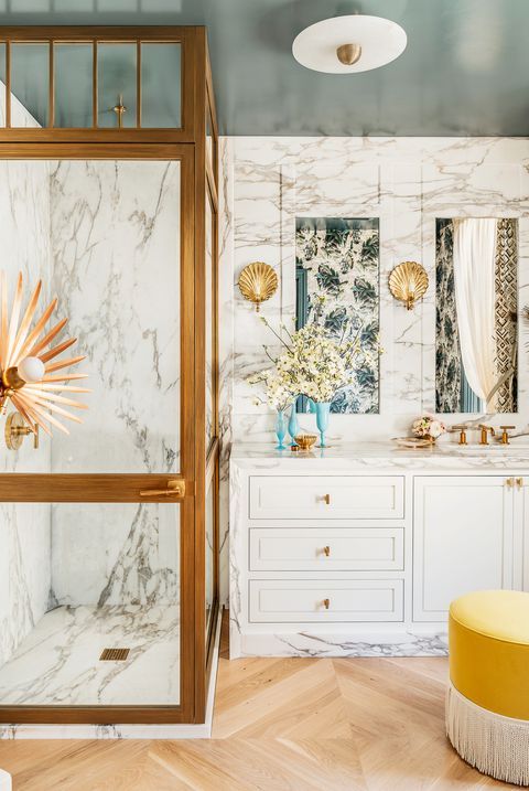 a fancy bathroom with white marble, a teal ceiling, white cabinets, gold touches and quirky lamps is a chic and lovely space
