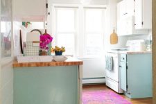 a light blue and white kitchen design with a pink rug