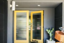 a lovely mid-century modern entrance with grey walls and yellow doors with reeded glass, a potted cactus and a bike