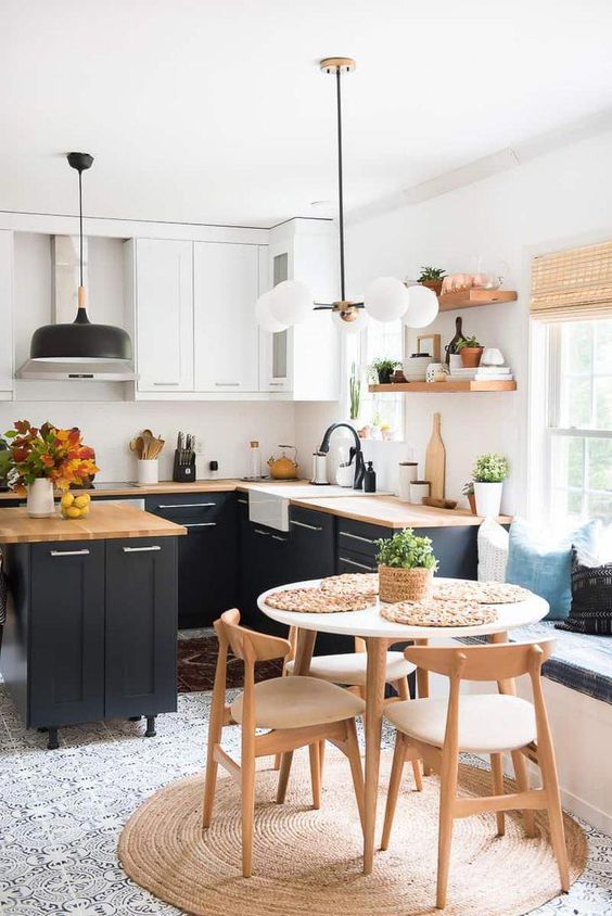 a lovely modern country kitchen with white and navy cabinets, butcherblock countertops, pendant lamps and black fixtures
