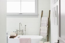 a modern country bathroom with white planked walls, a grey tile floor, white appliances, rough wooden accessories is cool