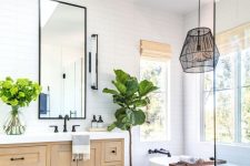 a modern country bathroom with white skinny tiles, a stained vanity, an oval tub, a pendant lamp and a skylight