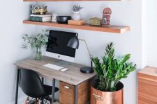 a modern country home office with floating shelves, an industrial desk with crate storage, a stool and a copper planter plus some greenery