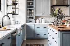 a modern country kitchen with light grey cabinets, butcherblock, white countertops, black fixtures and a vintage metal lamp