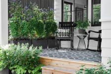 a modern farmhouse porch with a black printed rug, black rockers and printed pillows, potted plants and blooms is very cozy